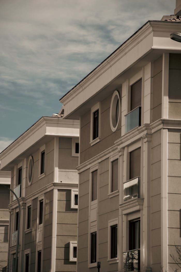 A modern urban building facade under a cloudy sky, showcasing architectural details and windows.