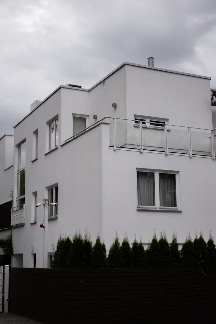 Contemporary white residential building against a cloudy sky.